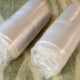 Two parts of couch in a mattress rolled in packaging.