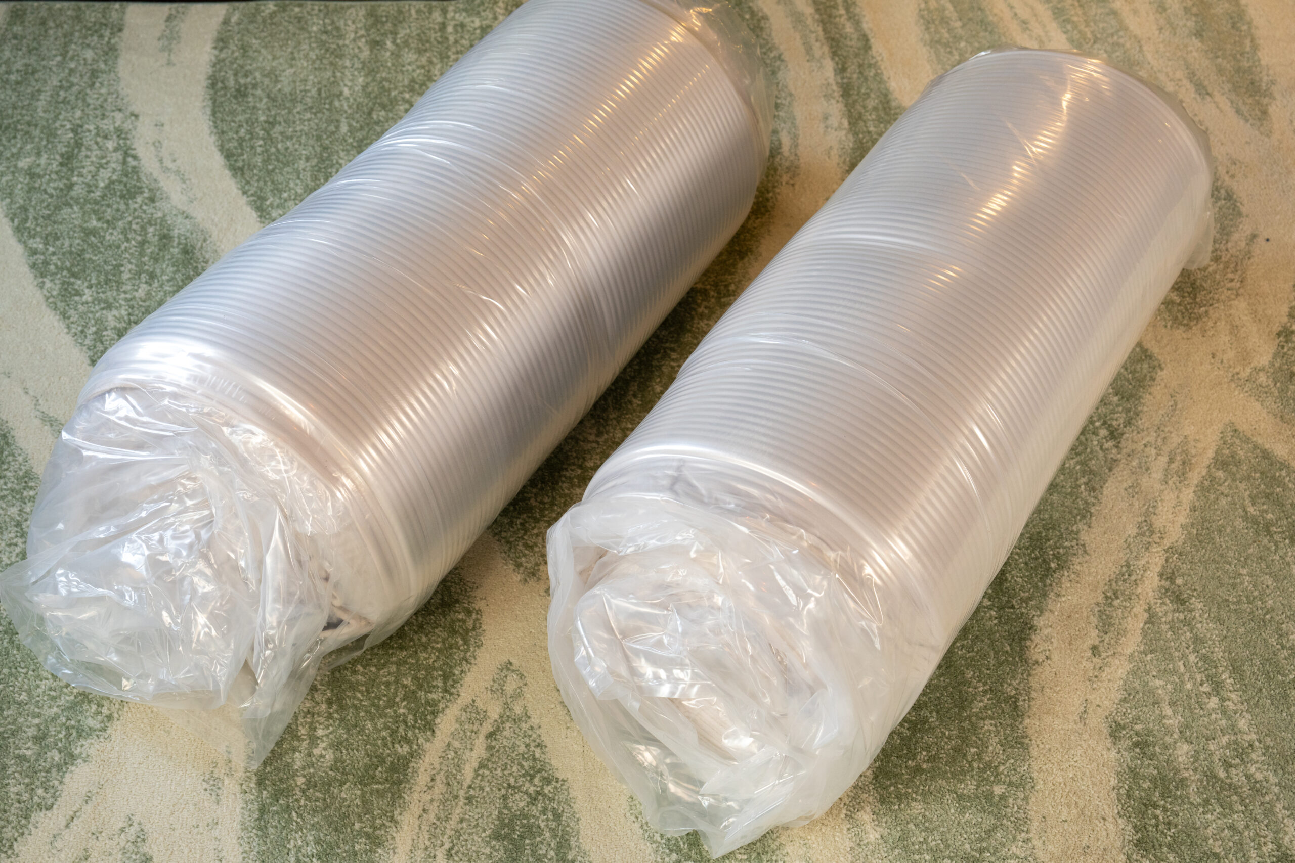 Two parts of couch in a mattress rolled in packaging.