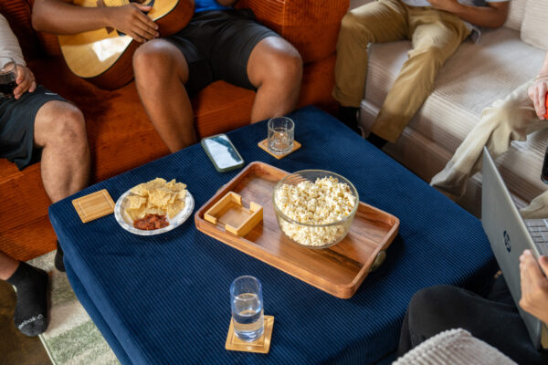 Wooden tray with bowl of popcorn on a blue ottoman.