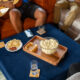 Wooden tray with bowl of popcorn on a blue ottoman.