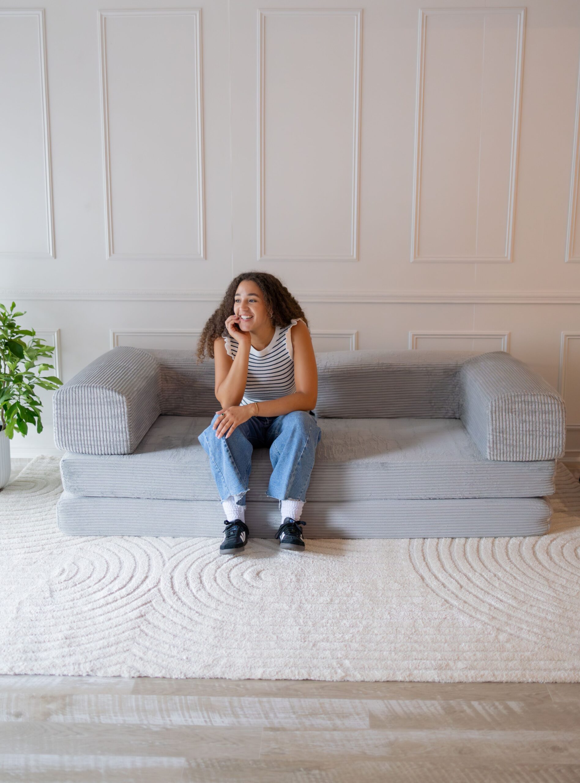 Young woman sitting on light grey 3-seater modular couch.