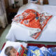 Young kid laying on dark red ottoman configured into a bed watching his ipad.