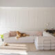 Large L Shaped couch with blue ottoman and dog on couch.