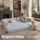 Woman sitting on gray boneless couch in expanded configuration with dog.