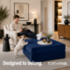 Man in white chair with feet up resting on navy blue foam ottoman with dog on back legs resting fronting legs on ottoman.