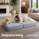 Woman laying with dog on gray boneless ottoman in bed configuration.