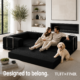 Couple and dog sitting on black boneless couch in expandable configuration.